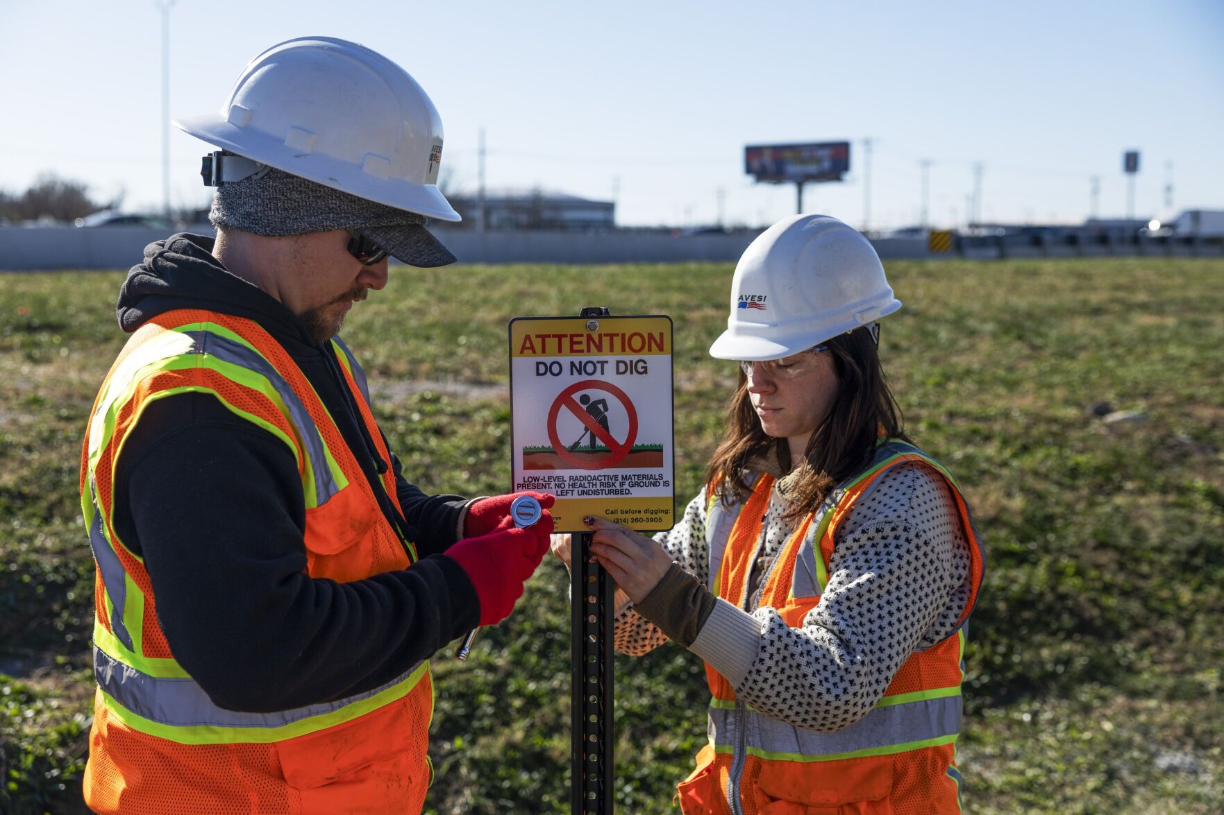 Contractors with the Army Corps of Engineers install signage along Coldwater Creek